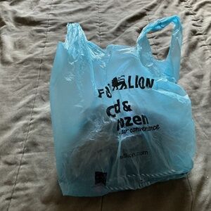 A blue bag with a ruin plushy and a gray bag and a 2 unused black socks